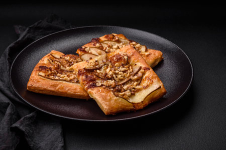 Delicious fresh sweet pie or pizza with pear, brie cheese, honey and nuts on a dark concrete backgroundの写真素材