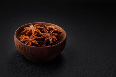 Star shaped spice star anise in a wooden round bowl on a dark concrete backgroundの写真素材