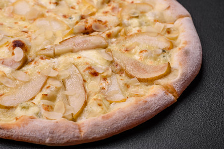 Delicious sweet pizza with pear, dorblu cheese and nuts on a dark concrete backgroundの写真素材