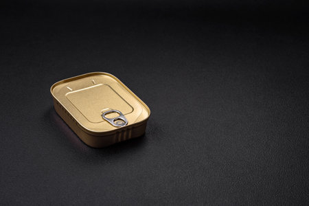 Tin or aluminum rectangular can of canned food with a key on a dark concrete backgroundの写真素材