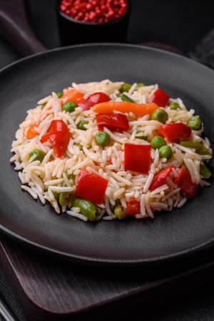 Delicious boiled rice with peppers, peas, asparagus beans and carrots on a textured concrete backgroundの写真素材