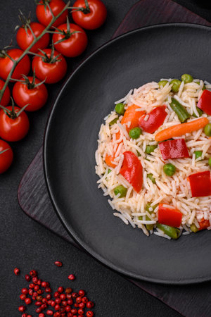 Delicious boiled rice with peppers, peas, asparagus beans and carrots on a textured concrete backgroundの写真素材