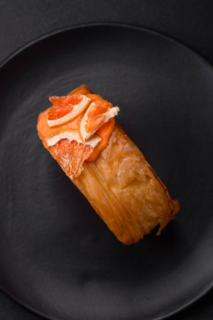 Round puff pastry croissant with citrus filling or New York roll on dark concrete backgroundの写真素材