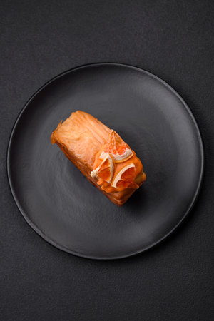 Round puff pastry croissant with citrus filling or New York roll on dark concrete backgroundの写真素材