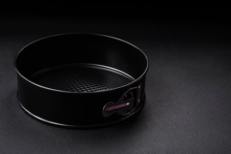 Round metal black detachable baking dish for baking on a dark concrete background