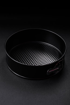 Round metal black detachable baking dish for baking on a dark concrete background