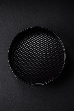 Round metal black detachable baking dish for baking on a dark concrete background