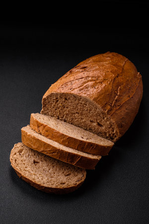 Delicious fresh crispy loaf of white bread with grains and seeds on a textural dark backgroundの写真素材