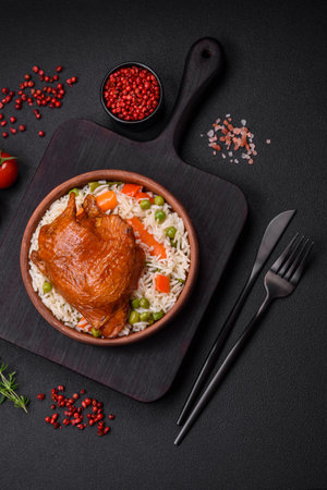 Delicious boiled rice with chicken and vegetables or risotto with salt, spices and herbs on a ceramic plate on a dark concrete backgroundの写真素材