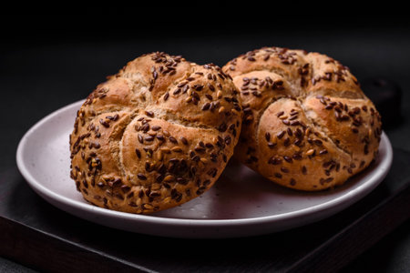 Delicious freshly baked crispy bun or kaiser roll with sesame seeds on dark concrete background