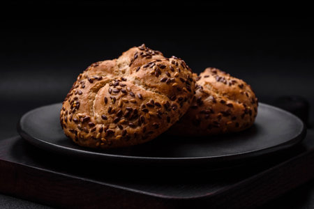 Delicious freshly baked crispy bun or kaiser roll with sesame seeds on dark concrete background