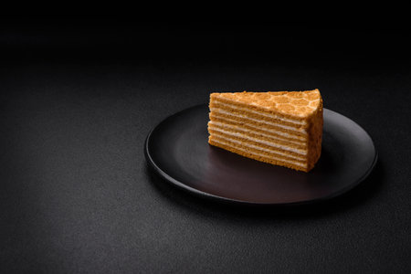 Delicious fresh sweet honey cake layer cake with white cream on textured concrete backgroundの写真素材