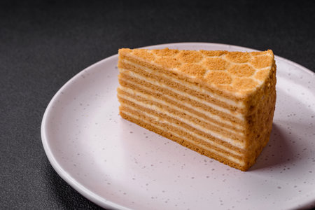 Delicious fresh sweet honey cake layer cake with white cream on textured concrete backgroundの写真素材
