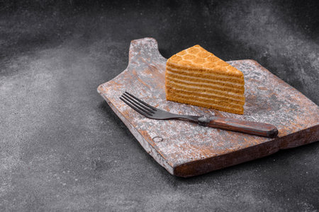 Delicious fresh sweet honey cake layer cake with white cream on textured concrete background
