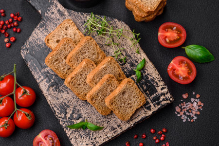 Delicious salted rectangular wheat croutons with salt and spices on a dark concrete backgroundの写真素材