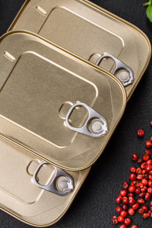 Tin or aluminum rectangular can of canned food with a key on a dark concrete background