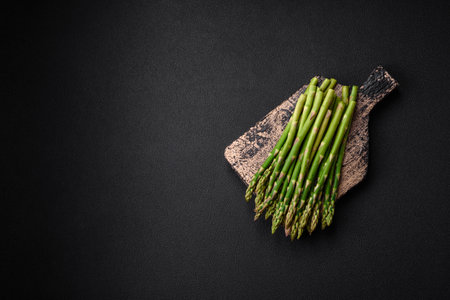 Delicious fresh sprigs of asparagus on a dark textured background. Ingredients for a vegetarian healthy mealの写真素材