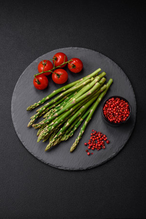 Delicious fresh sprigs of asparagus on a dark textured background. Ingredients for a vegetarian healthy mealの写真素材