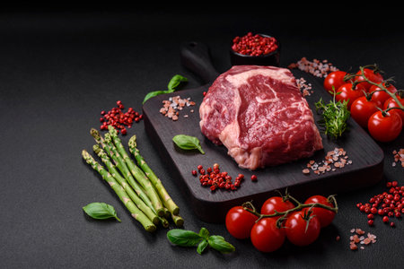 Fresh, raw beef steak with salt, spices and herbs on a dark textured backgroundの写真素材