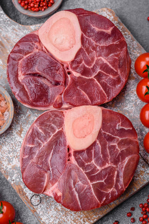 Fresh raw beef steak with bone or ossobuco with salt, spices and herbs on dark concrete backgroundの写真素材