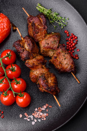 Delicious grilled chicken, turkey or pork skewers with salt, spices and herbs on a fire on a dark concrete backgroundの写真素材