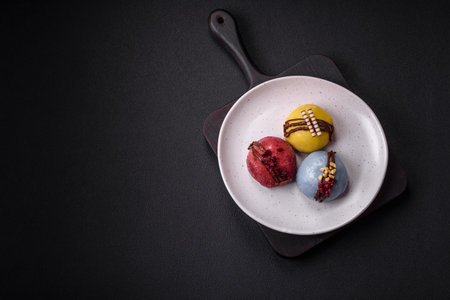 Delicious sweet colorful mochi desserts or ice cream with rice dough and toppings on a dark concrete...