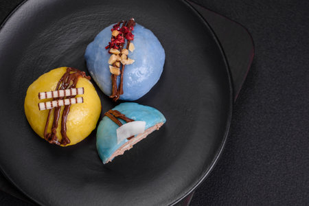 Delicious sweet colorful mochi desserts or ice cream with rice dough and toppings on a dark concrete backgroundの写真素材