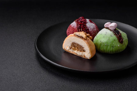 Delicious sweet colorful mochi desserts or ice cream with rice dough and toppings on a dark concrete...