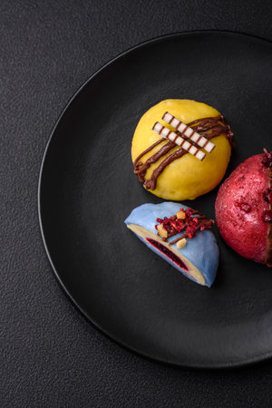 Delicious sweet colorful mochi desserts or ice cream with rice dough and toppings on a dark concrete...