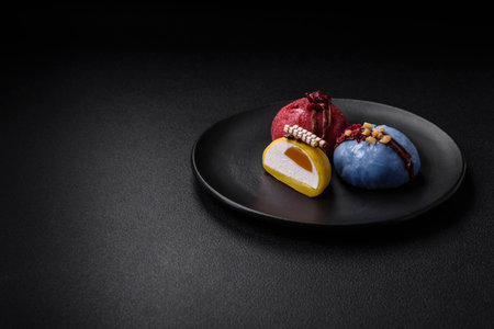 Delicious sweet colorful mochi desserts or ice cream with rice dough and toppings on a dark concrete backgroundの写真素材