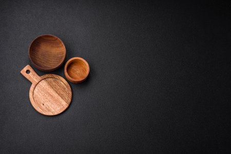 Empty round kitchen wooden cutting board in brown color on a dark textured concrete background