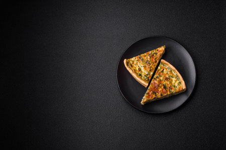 Delicious fresh quiche with broccoli, cheese, spices and herbs cut into pieces on a dark concrete...