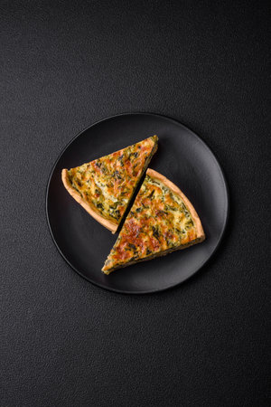 Delicious fresh quiche with broccoli, cheese, spices and herbs cut into pieces on a dark concrete backgroundの写真素材