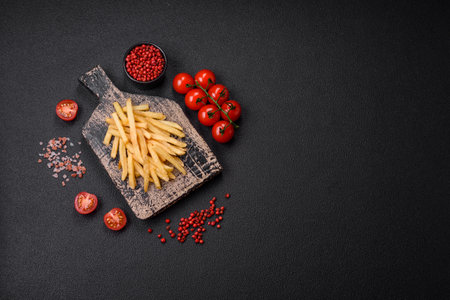 Delicious crispy french fries with salt and spices on a textured concrete background. fast food