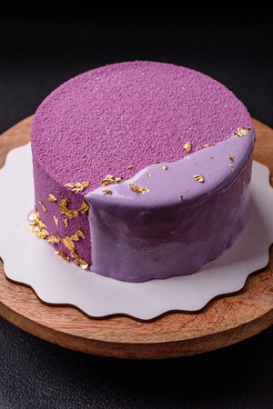 Delicious fresh sweet mousse cake with berry filling topped with pink velvet topping on dark concrete backgroundの写真素材
