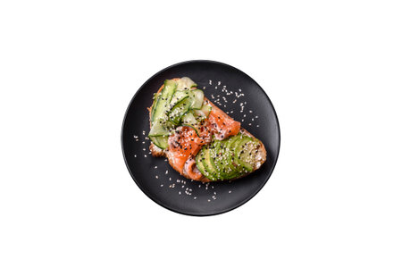 Fresh tasty sandwich with salmon, avocado and sesame and flax seeds on a dark concrete background