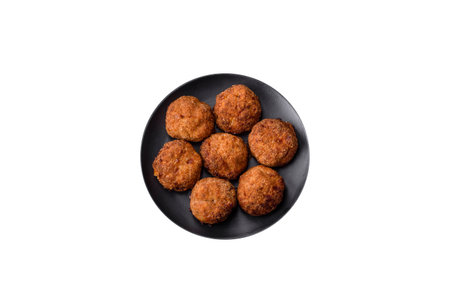 Delicious fresh meat or vegetable cutlets with spices and herbs on a black plate on a dark concrete...