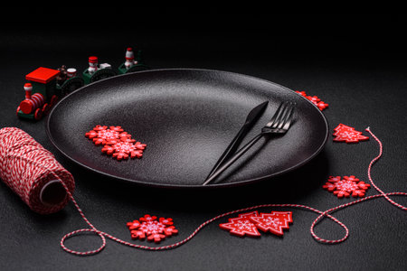 Empty ceramic black plate with christmas decoration elements on holiday textured concrete backgroundの写真素材
