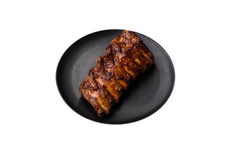 Delicious grilled pork ribs with sauce, spices and herbs on a dark concrete background