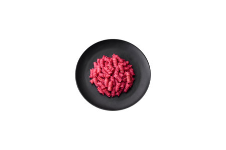Delicious fusilli pasta with beetroot pesto, parmesan, salt and spices on a dark concrete backgroundの写真素材