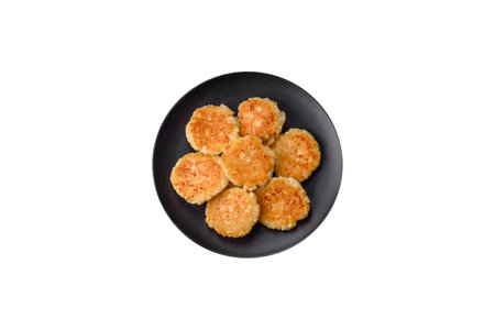 Delicious fresh cottage cheesecakes with raisins and vanilla on a black ceramic plate on a dark concrete backgroundの写真素材