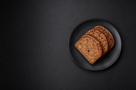Delicious fresh crispy brown bread with grains and seeds on a dark concrete backgroundの写真素材