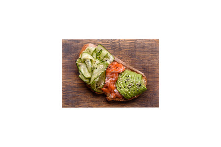 Delicious brown bread toast with salmon, avocado, cucumber and sesame seeds on a textured concrete backgroundの写真素材