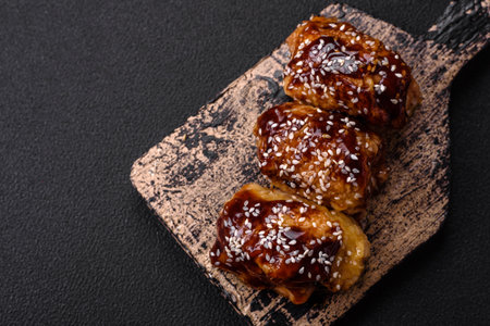 Delicious juicy fried chicken with sweet and sour teriyaki sauce and sesame seeds on a dark concrete backgroundの写真素材