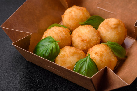 Delicious round balls of mozzarella and parmesan cheese with salt and breaded spices on a dark concrete background. Fast food, unhealthy foodの写真素材