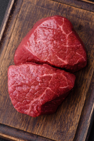 Fresh juicy raw beef medallions with salt and spices on a dark concrete backgroundの写真素材