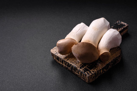 Pleurotus eryngii mushrooms on a dark concrete background. Raw whole edible mushroomsの写真素材