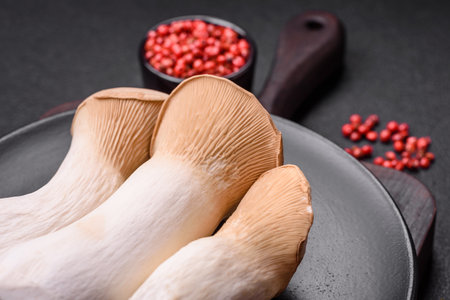 Pleurotus eryngii mushrooms on a dark concrete background. Raw whole edible mushroomsの写真素材