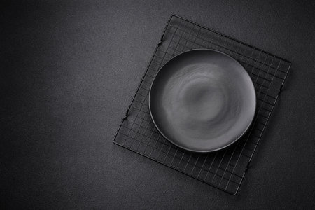 Empty ceramic round plate on dark textured concrete background. Cutlery, preparation for dinnerの写真素材