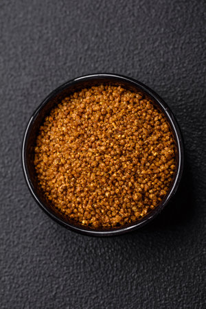 Crystals of brown Svan salt with spices in a black bowl on a dark concrete backgroundの写真素材
